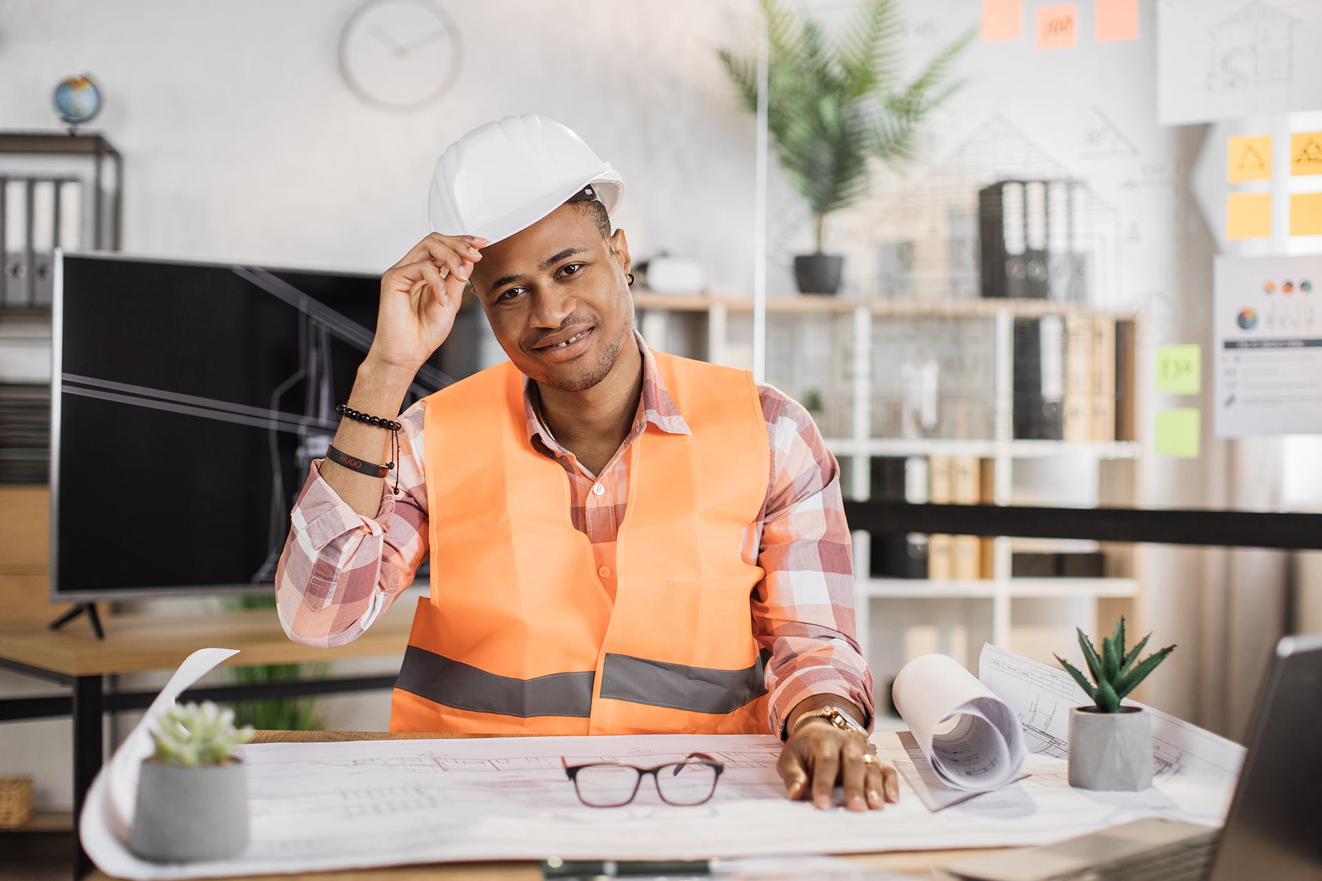 A general contractor smiling while a blueprint plan of house laid on the table.