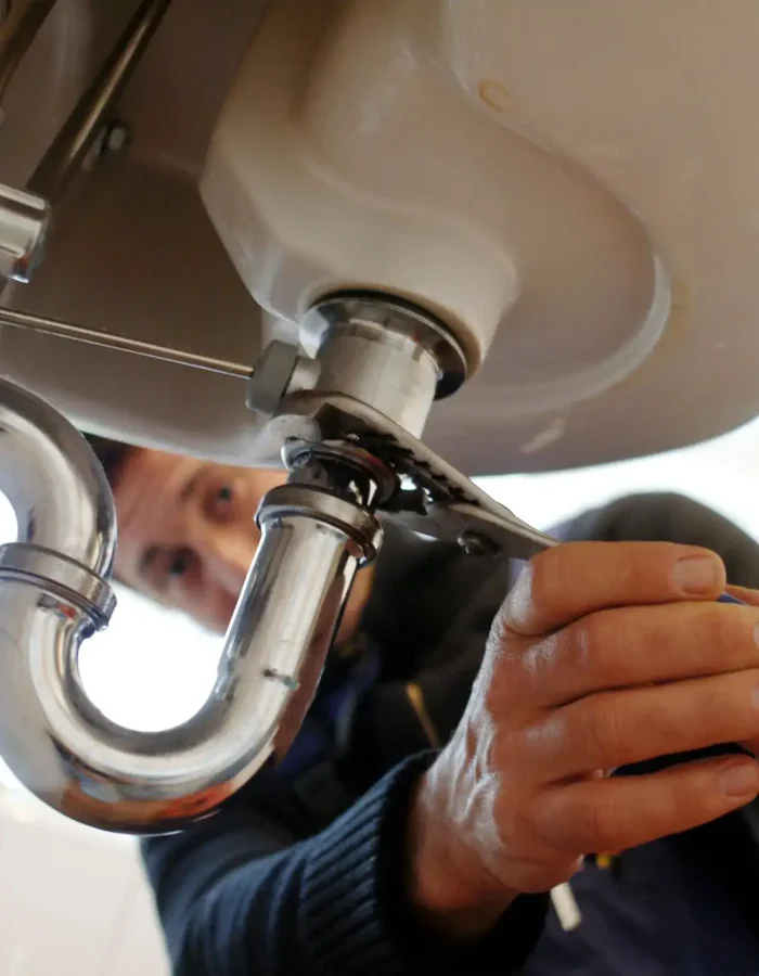 A close-up of a plumber fixing the sink.